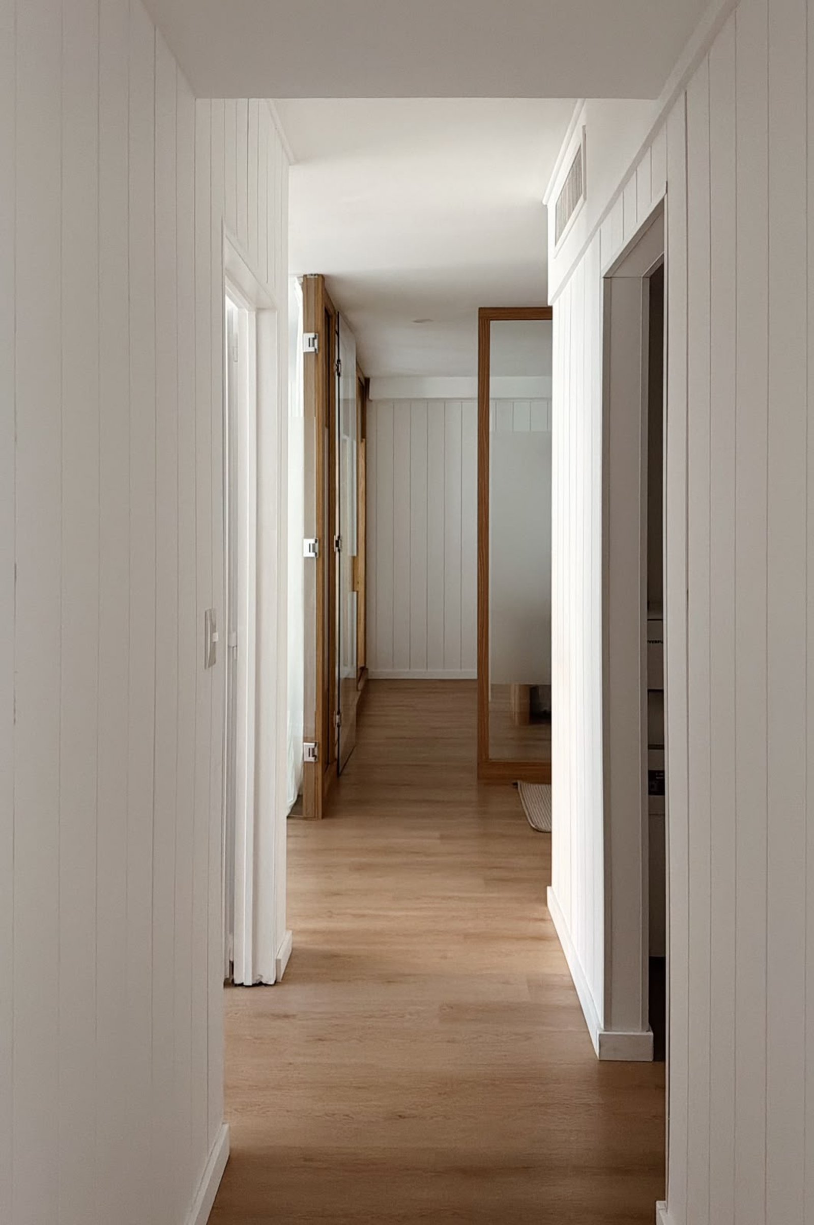 Pasillo moderno minimalista con paneles de madera blanca — proyecto PICO, por APATHEIA, en Cdad. Autónoma de Buenos Aires